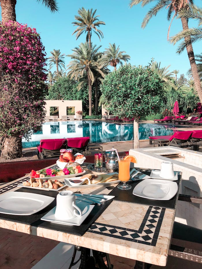 Enjoy a luxurious outdoor dining experience by the pool with lush greenery and delicious breakfast.