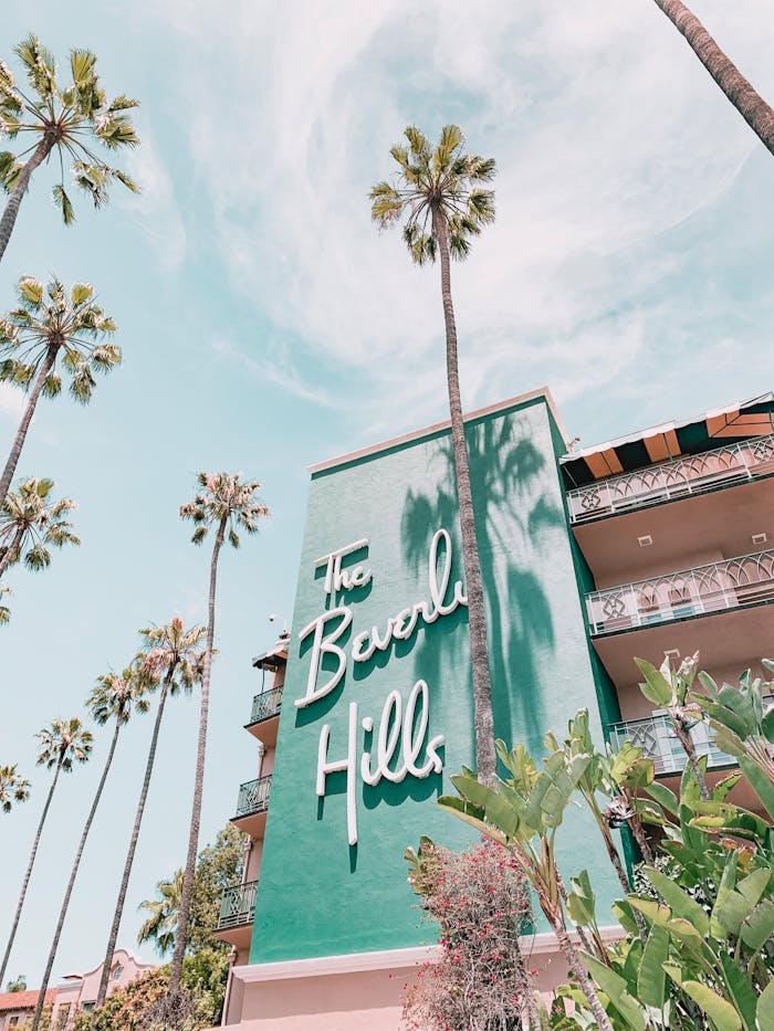 The Beverly Hills Hotel with palm trees under a clear sky. Iconic luxury in Los Angeles, California.